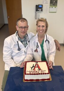 drs-adam-and-autumn-terry-sitting-in-front-of-a-cake-that-reads-celebrating-20-years-of-amazing-care